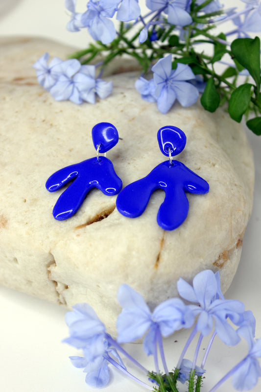 Boucles d'oreilles bleu Klein inspirées par les œuvres de Henri Matisse et de Yves Klein, de forme abstraite évoquant les algues ou les feuilles, en argile polymère, résine et argent plaqué. Pièces uniques fabriquées à la main sur la Côte d'Azur.