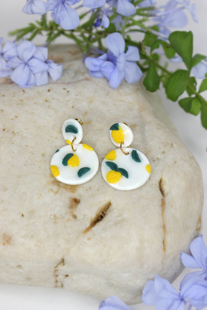 Boucles d'oreilles blanches vernies avec petits citrons sculptés, en argile polymère, résine et or plaqué.  Entièrement fabriquées à la main sur la Côte d'Azur dont elles s'inspirent.