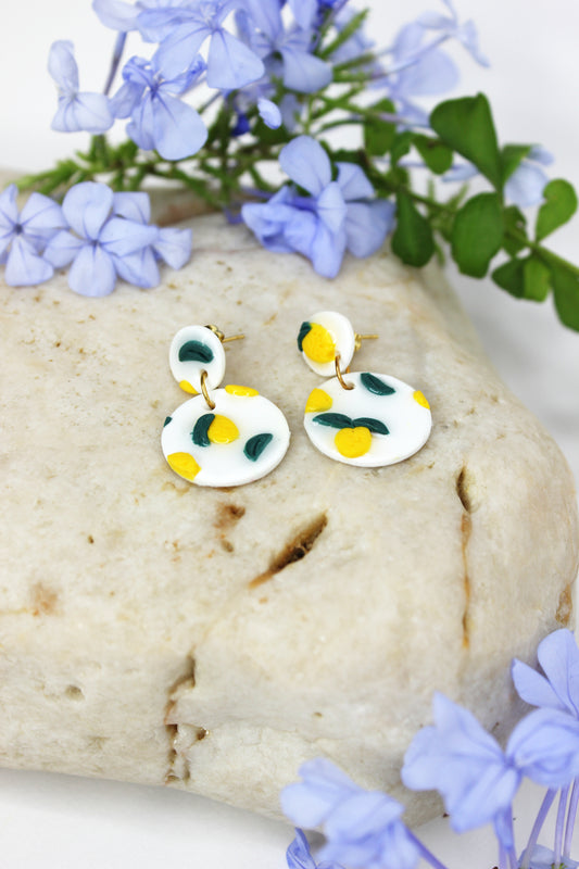 Boucles d'oreilles blanches vernies avec petits citrons sculptés, en argile polymère, résine et or plaqué.  Entièrement fabriquées à la main sur la Côte d'Azur dont elles s'inspirent.