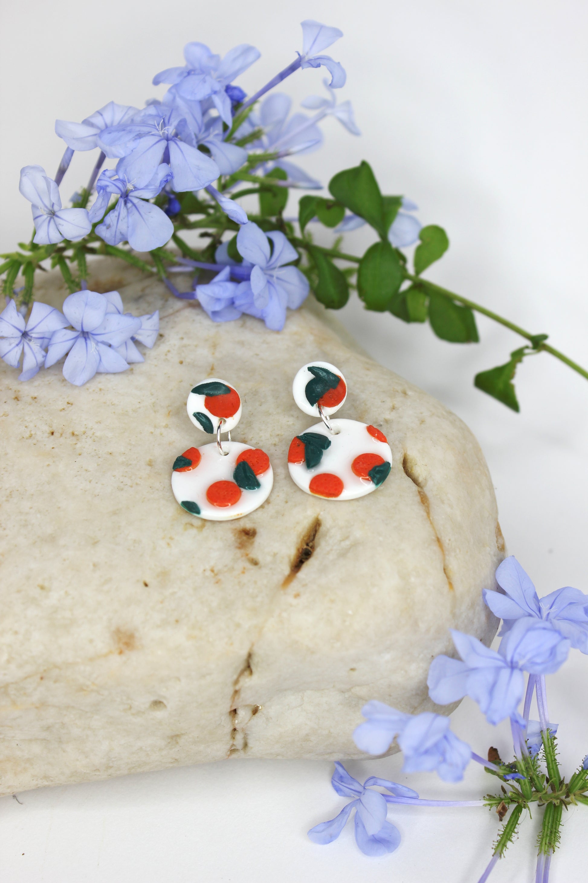 Boucles d'oreilles blanches vernies avec oranges sculptées, inspirées des agrumes de la Méditerranée. Entièrement fabriquées à la main sur la Côte d'Azur, en argile polymère, résine et argent plaqué.