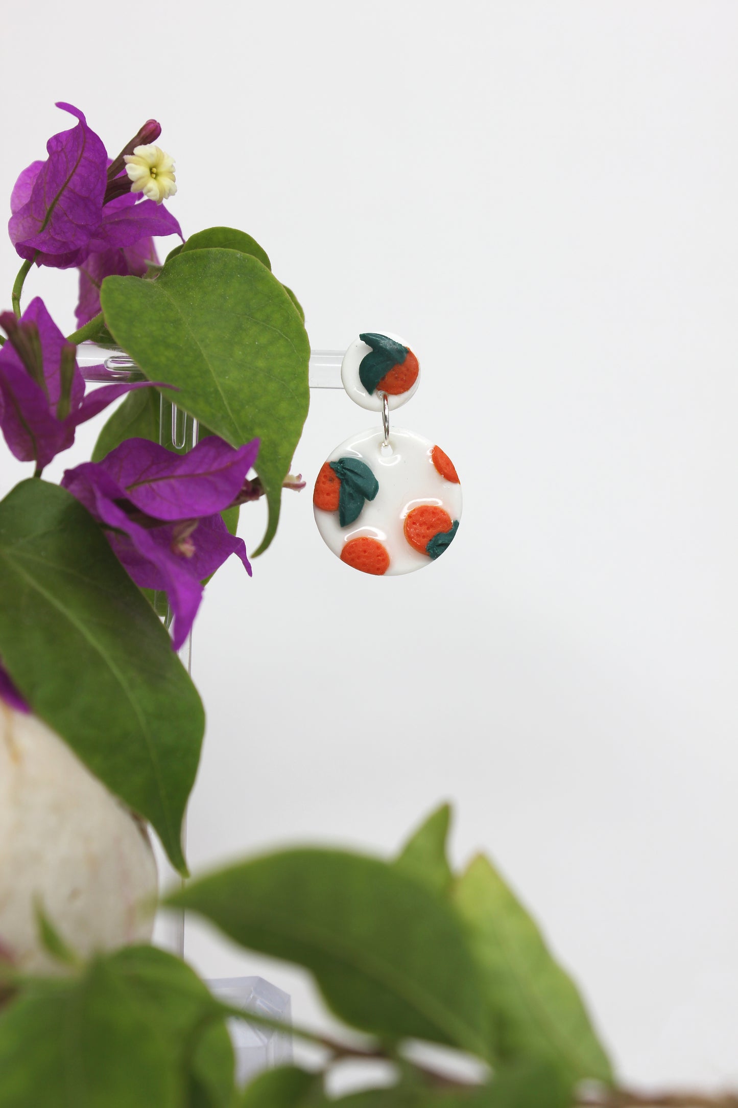 Boucles d'oreilles blanches vernies avec oranges sculptées, inspirées des agrumes de la Méditerranée. Entièrement fabriquées à la main sur la Côte d'Azur, en argile polymère, résine et argent plaqué.