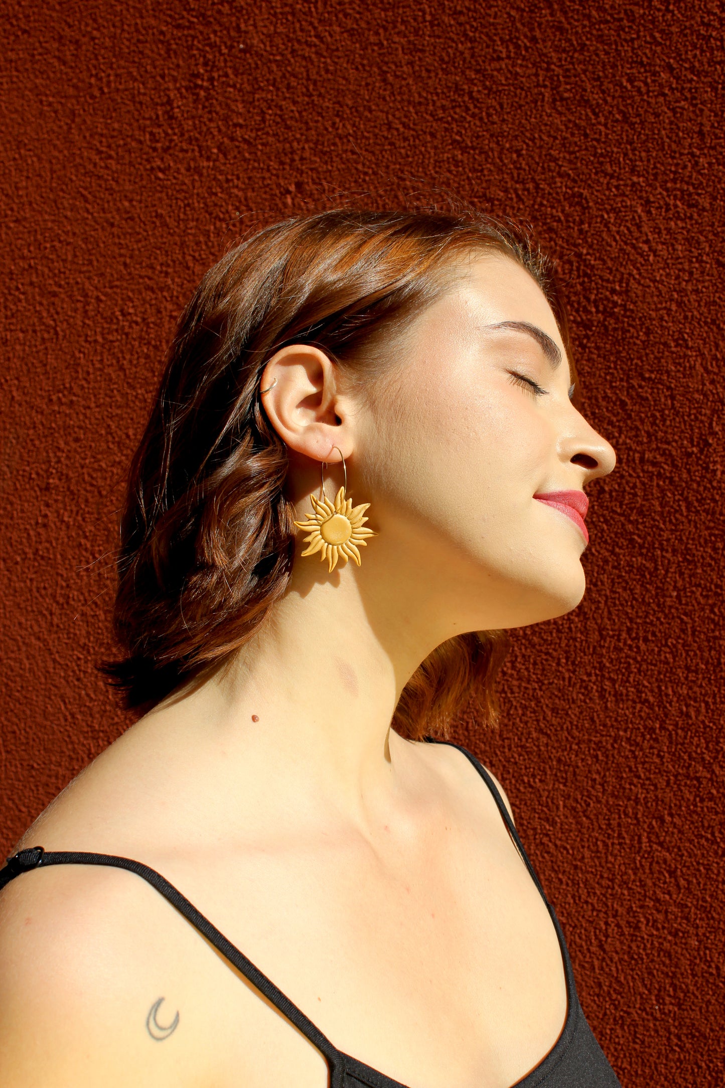 Boucles d'oreilles créoles avec pendentif  en forme de soleil, de couleur dorée, en argile polymère et acier inoxydable doré. Fabriquées à la main sur la Côte d&#39;Azur